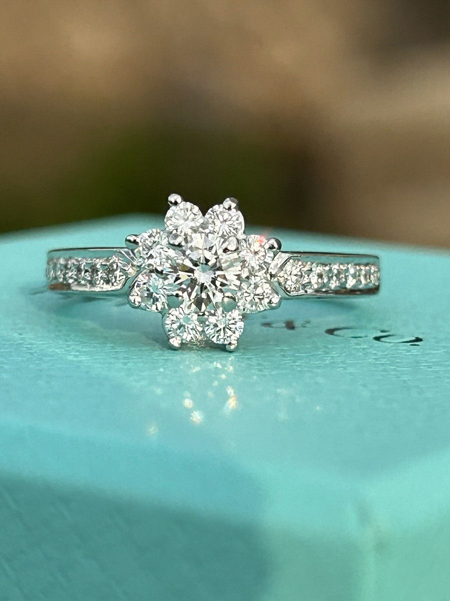 A diamond cluster ring in the shape of a flower, resting on a ring box.
