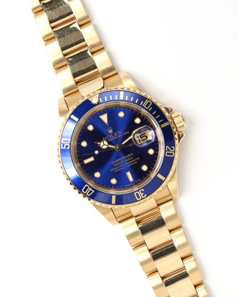 A yellow-gold dive watch with a purple-blue dial and matching bezel on a gold bracelet.